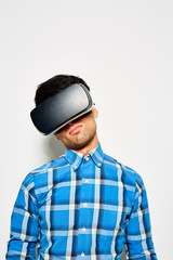 Waist-up portrait of dark-haired young designer wearing VR goggles while working on promising project, studio shot