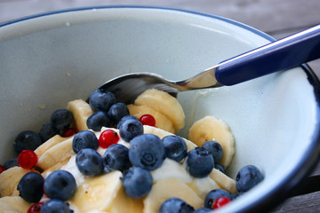 A close-up of a breakfast bowl of fresh fruits and Greek yogurt on a rustic wooden table