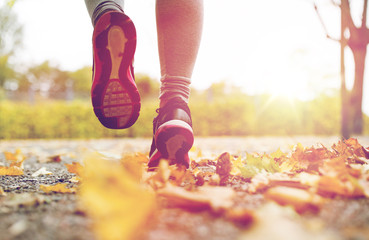 close up of young woman running in autumn park