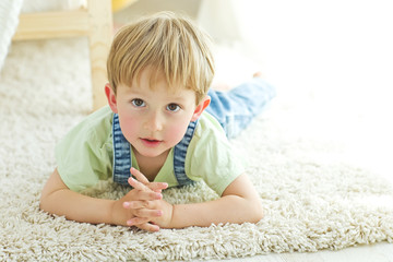 The child lies on the carpet