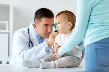 doctor checking baby ear with otoscope at clinic