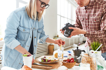 Talented food stylist and photographer gathered together at modern production studio with panoramic...