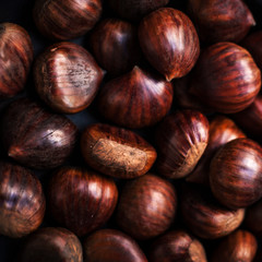 Ripe chestnuts in a frying pan on old wooden table  close up with copy space. Roasted Chestnuts for Christmas.