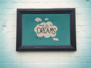 Never let go of your dreams cloud and sky in black frame on white wall background