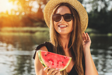 Sweet summer moments outdoors. Closeup of attractive and young woman in hat and sunglasses keeping...