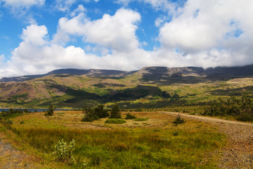 Iceland, southern region. Typical icelandic landscape - mountains, green valley, hills, sky and clouds.  Green and blue scene.