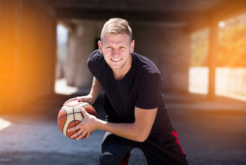 Good looking tall blonde male holding basket ball ready for crossover dribble