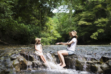 Mother and daughter playing on mountain stream