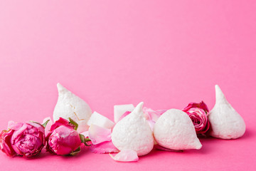 White meringues and roses buds at pink background