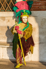 Fototapeta na wymiar Costumed person in Venetian mask during Venice Carnival in Venice