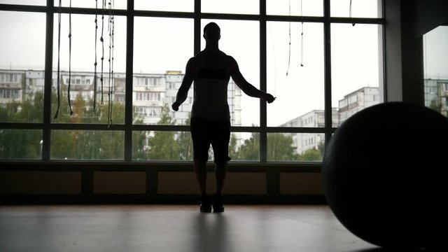 Muscular man doing rope jump work-out in the gym - silhouette, slow-motion