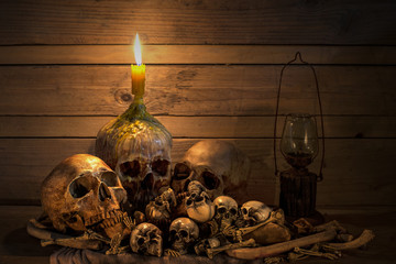 Human skulsl and pile bone with candle Light, Still life style onold wooden table