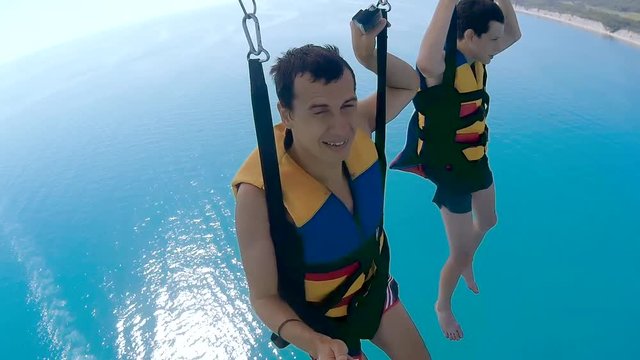 paragliding and parasailing lifestyle. man and boy are flying ocean on a parachute over the sea. Extreme sport first-person view