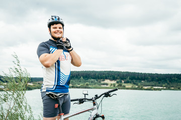 man near standing near lake with bicycle and check helmet