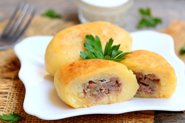 Potato zrazy with a meat filling on a white plate and a vintage wooden table. Traditional Ukrainian zrazy recipe. Closeup