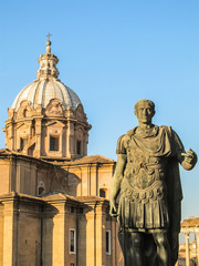Rome - June 2015: Statue of Cesar at the Roman Forum, church dome in the background