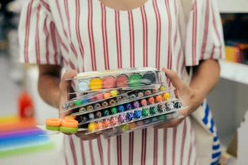 Mother choosing buying stationery in store preparing for first day in school. Closeup on buyer hands holding goods. Busy blurred shopping indoors background © gorosi