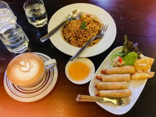 Cappuccino and water on the table with glass of water and spaghetti