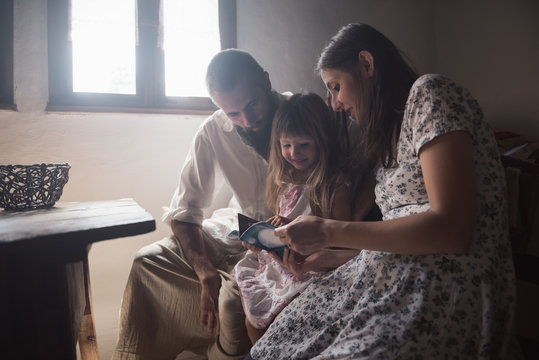 Little girl looking inside a book together with her parents