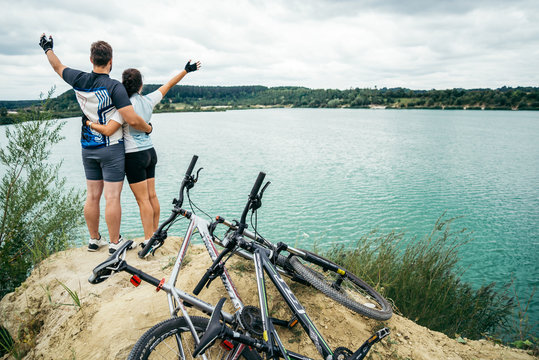 cuple of sportmen sitting near lake with bicycles