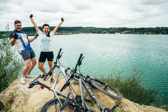cuple of sportmen sitting near lake with bicycles