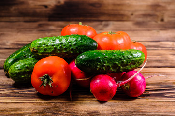 Ripe tomatoes, radish and cucumbers on wooden table
