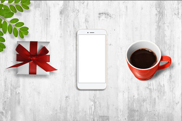 White smartphone with isolated screen on the table, surrounded with gift box, coffee and plant