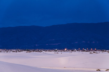 A beautiful blue sunset at White Sand Dunes National Monument with Alamagordo city at night