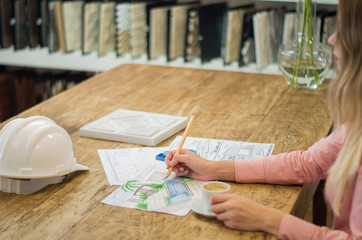 Mulher jovem bonita trabalhando em planta de arquitetura, mesa de madeira
