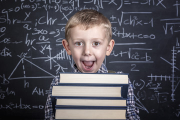 Caucasian child with plaid shirt and braces in front of a classic slate school blackboard. happy and positive expression.