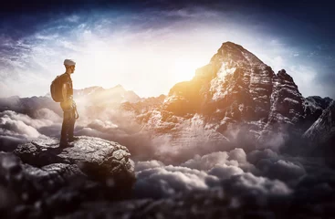 Fotobehang Bergbeklimmer staat bovenop en kijkt in de verte naar een grote berg © XtravaganT