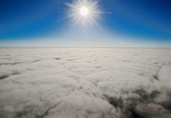 vista porencima de las nubes, con el fondo del sol, montañas y cielo azul hecha la foto desde un globo