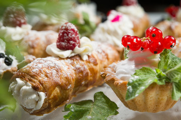 Cupcakes with cream with a leaf mint, currant red fresh. Tub with cream and raspberry.