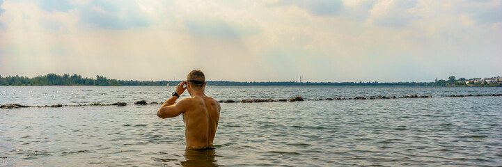Man preparing for an openwater swim in a lake, panorama