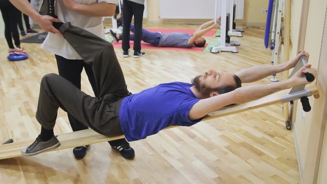Physiotherapist helping young man, doing exercises at the rehabilitation center. Healthy gymnastics. Active people.