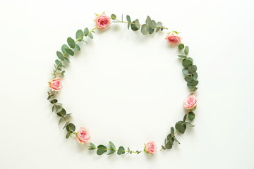 frame from eucalyptus branches and pink roses on white background. Flat lay, top view. copy space