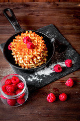 waffles with raspberries on wooden background