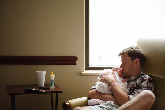 New father holds newborn baby in hospital