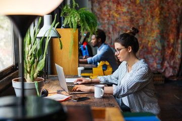 Side view of colleagues working on their desks in a creative office.
