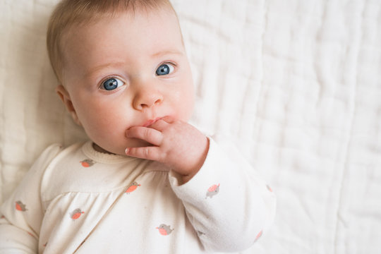 Close-up of baby girl sucking her fingers into mouth