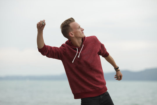 Blond man throwing stone in river