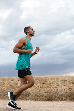 Side view of a runner training on a fiel path in autumn.