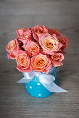 pink-orange roses in a turquoise box tied with a bow