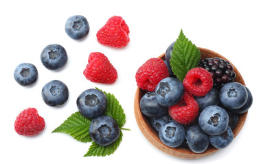mix of blueberries, blackberries, raspberries in wooden bowl isolated on white background. top view