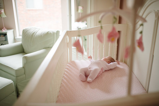 Awake baby girl lies in crib