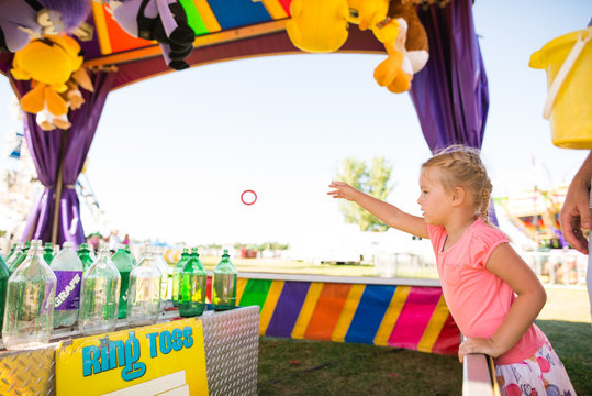 Young girl throws ring toss at county fair game