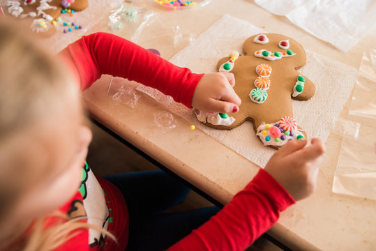 Young girl decorates gingerbread man cookie