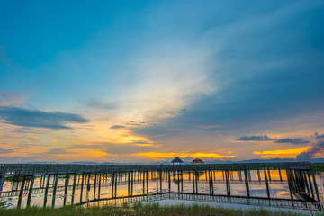 Beautiful romantic golden sunset and wooden bridge at pond. Fantastic vivid twilight at Sam Roi Yod National Park, Prachuap Khirikhan, Thailand.