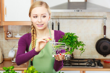Woman holding shopping cart with parsley inside