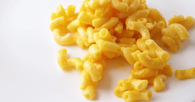 Close video of macaroni and cheese that has been microwaved being dumped onto a white plate..